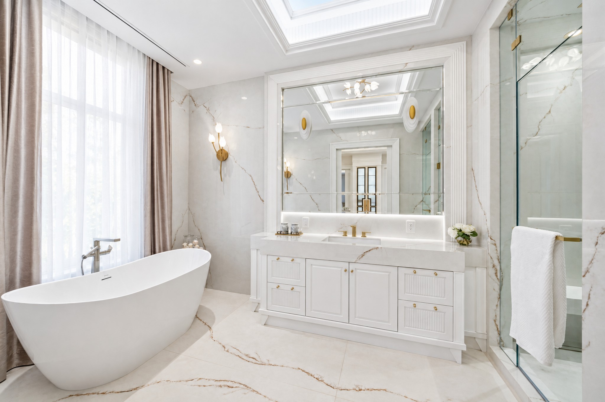 Ensuite with oval freestanding tub, gold-veined stone walls, skylight and glass shower