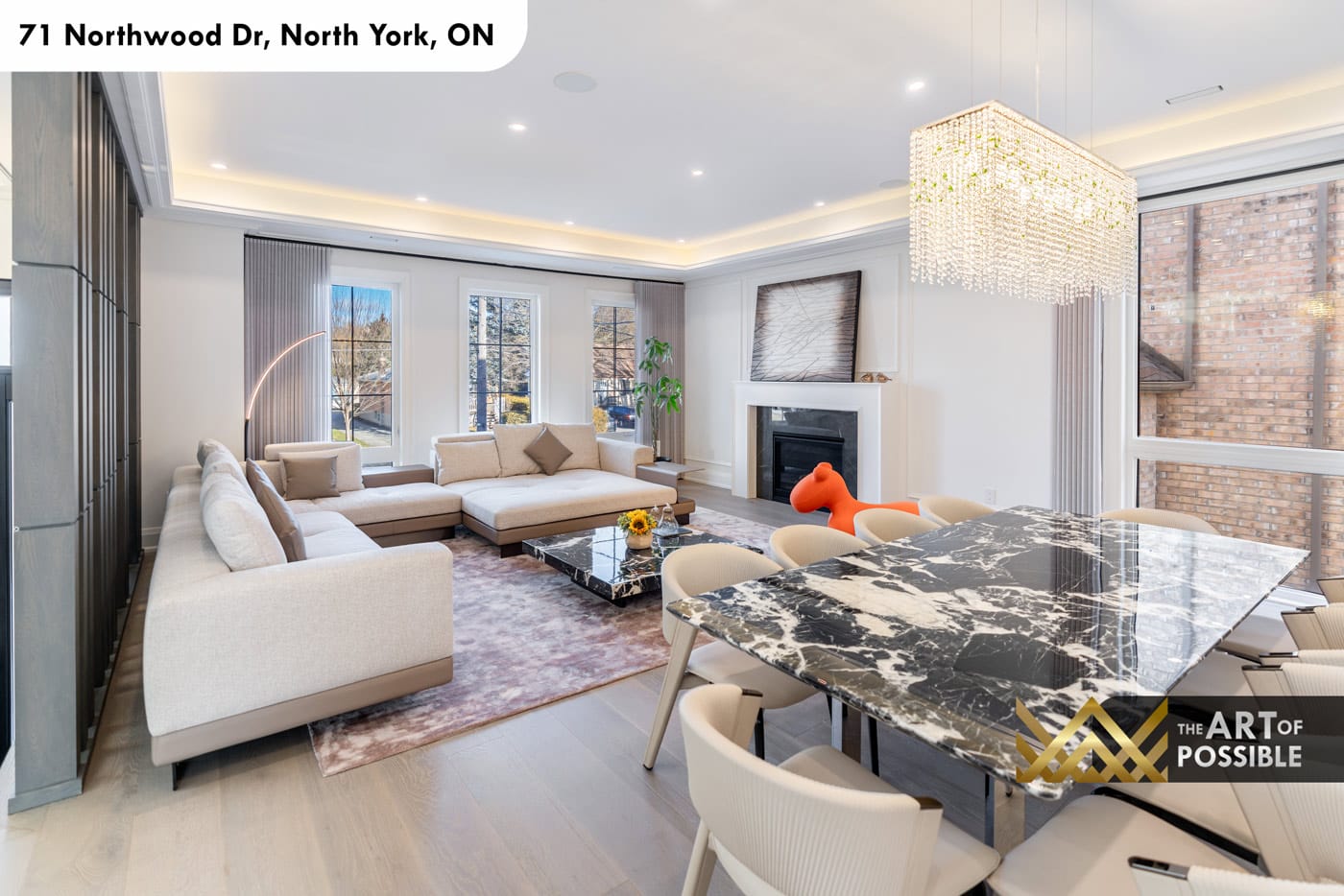 Main floor open-plan living and dining with dark marble dining table and crystal chandelier