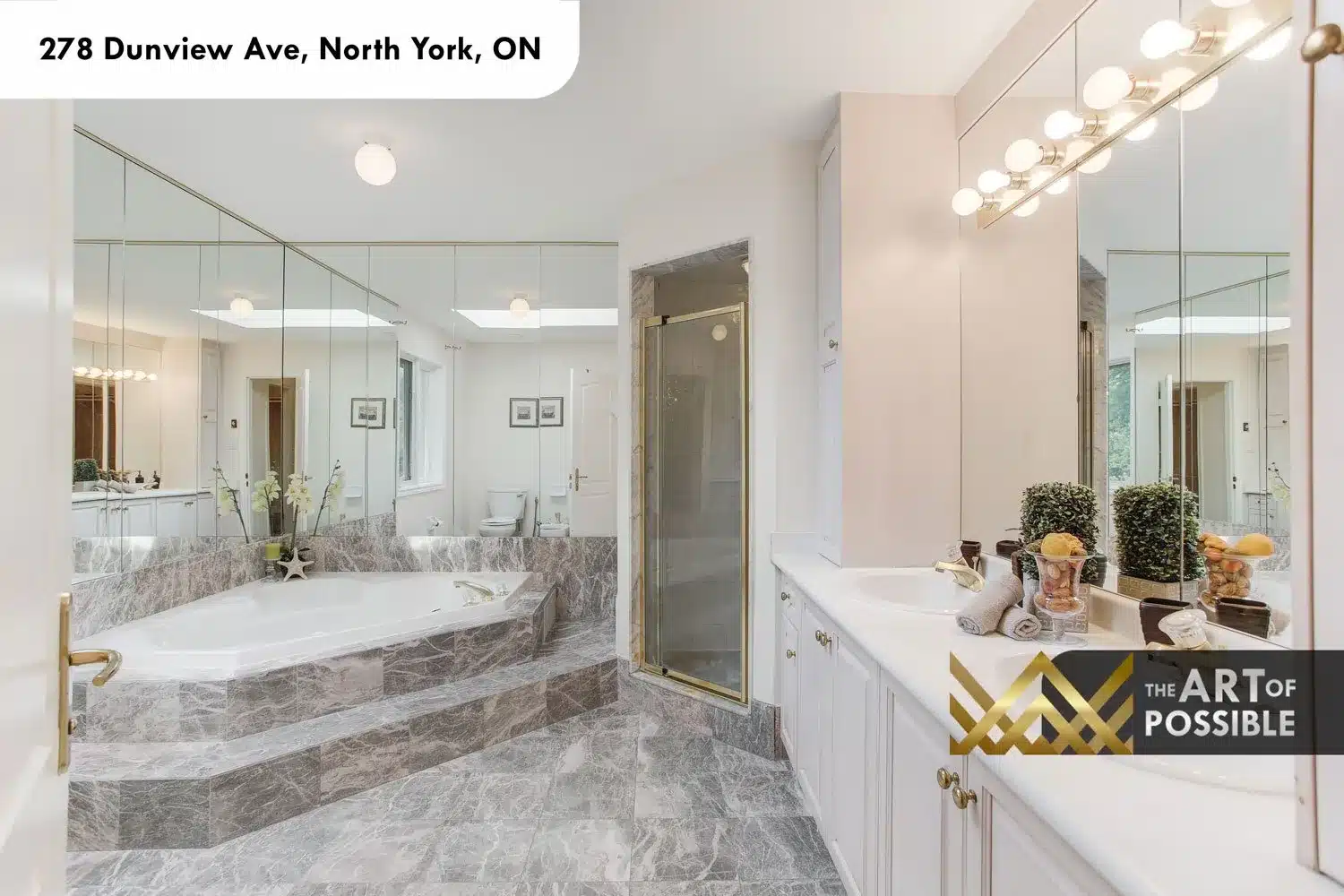 Primary ensuite with grey marble floors and tub surround, platform soaker tub, gold fixtures, floor-to-ceiling mirrors