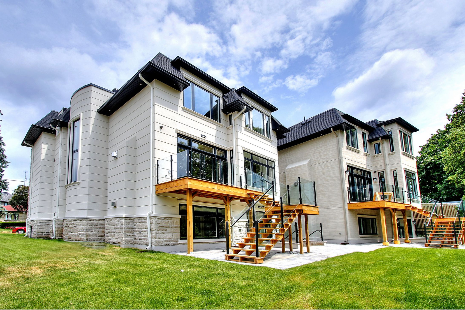 Rear exterior of the KingsGate homes at 203 Newton Drive with elevated wooden decks, glass railings and a stone patio