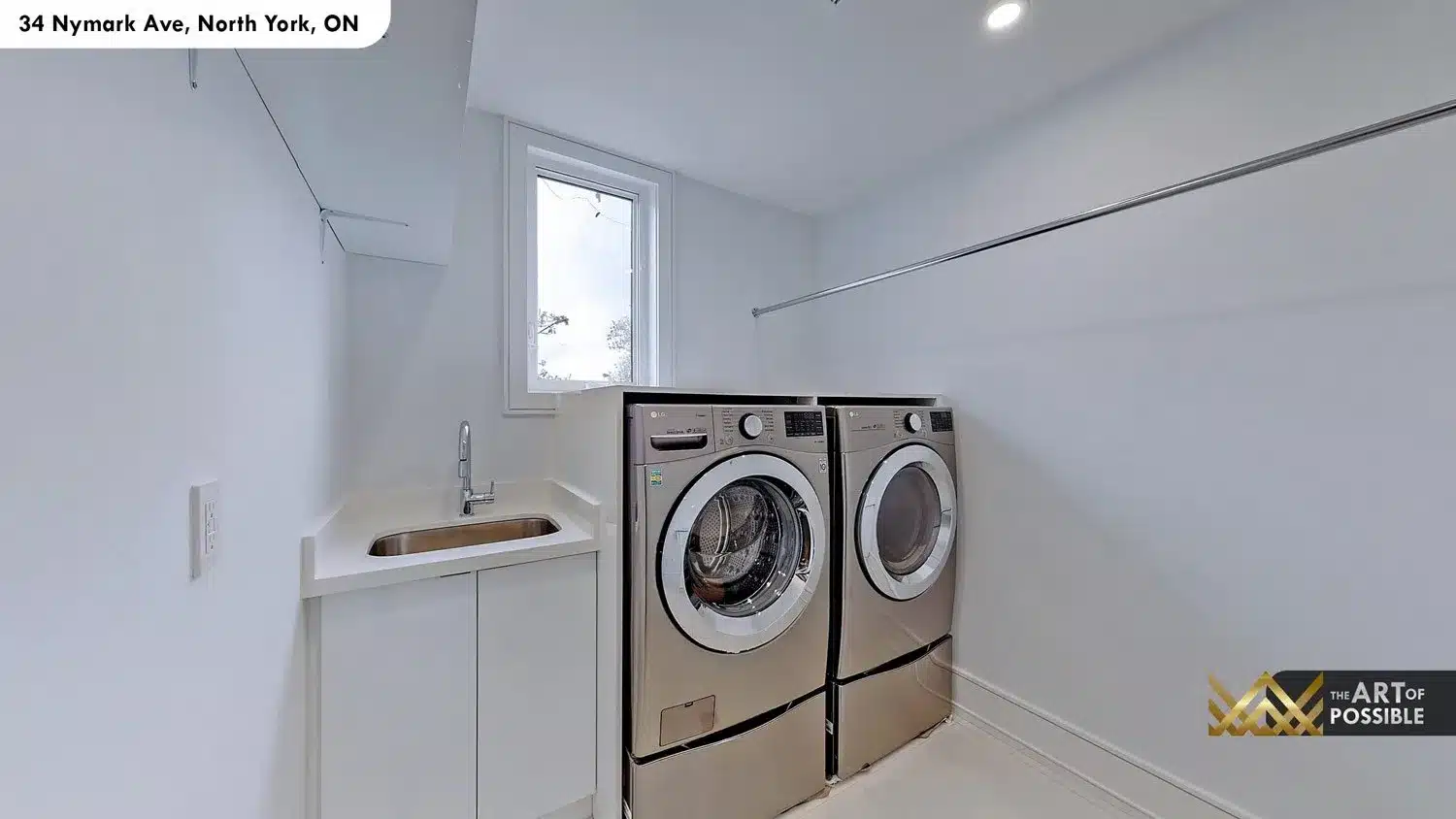 Dedicated laundry room with LG front-load washer and dryer on pedestals and white cabinetry with utility sink