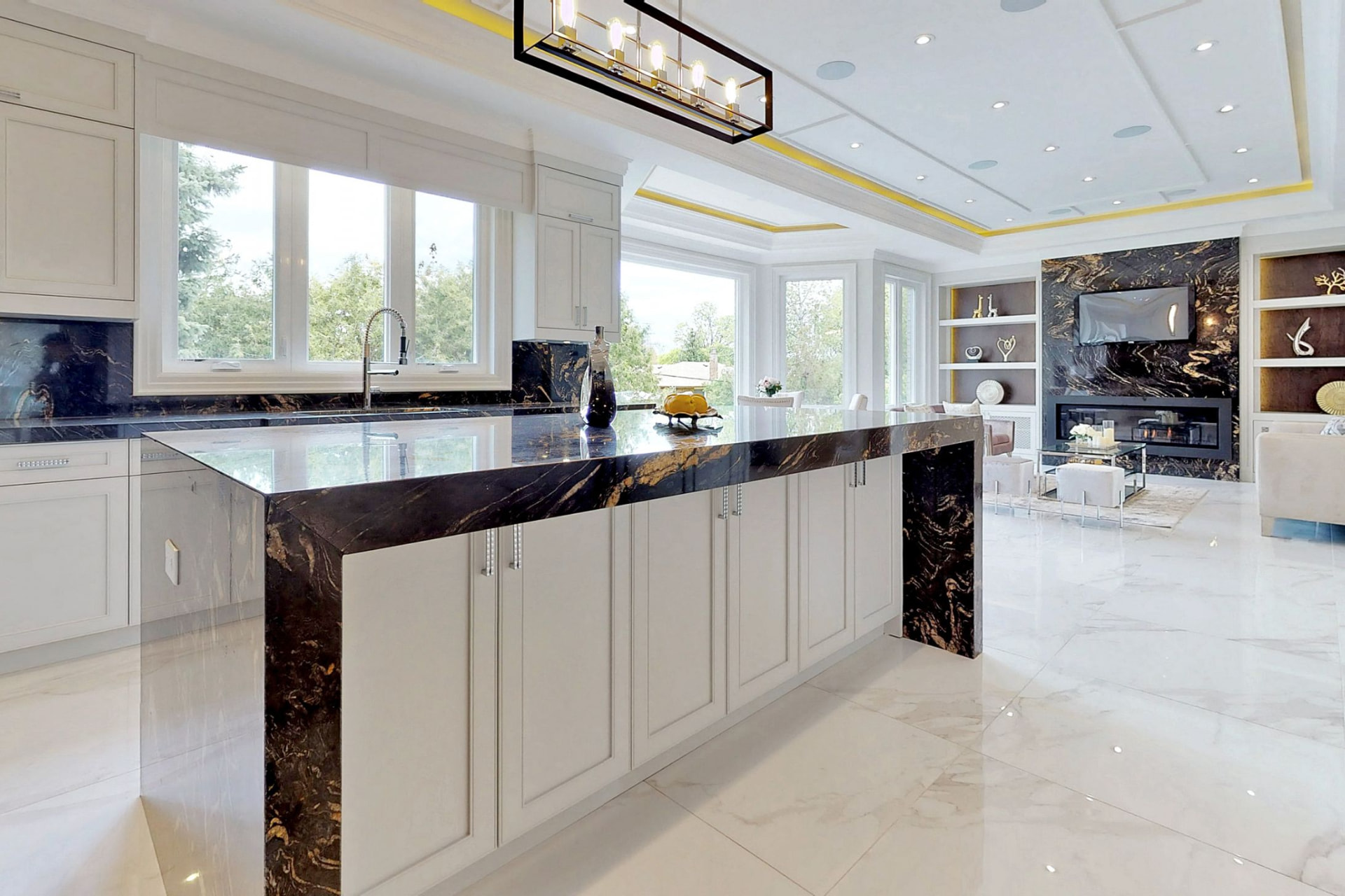 KingsGate kitchen with a black veined marble waterfall island, white cabinetry and a view into the living area