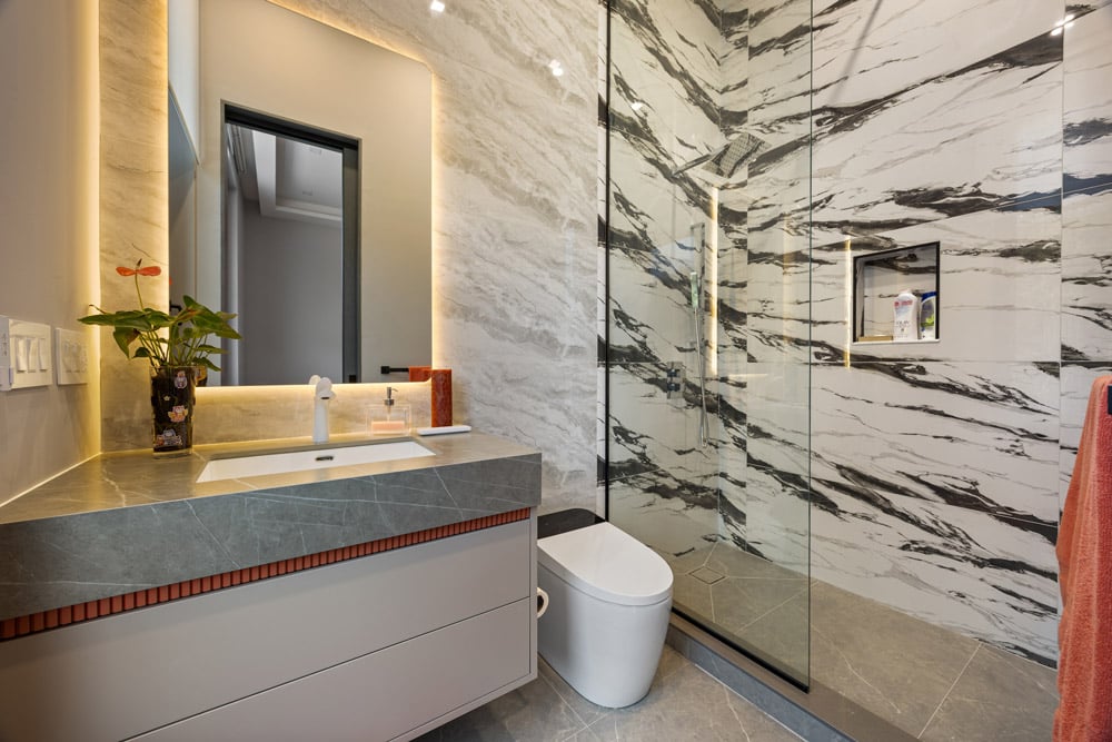 Secondary ensuite with marble slab shower walls, coral reeded accent detail on white floating vanity and LED backlit mirror