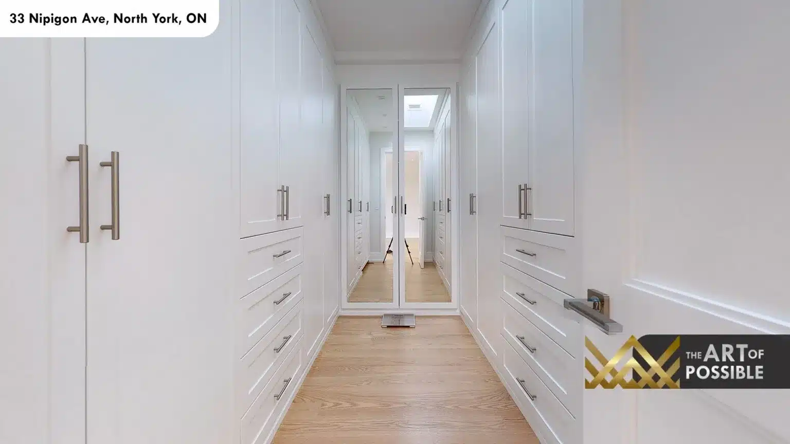 Walk-in closet corridor with white custom cabinetry and skylight at far end