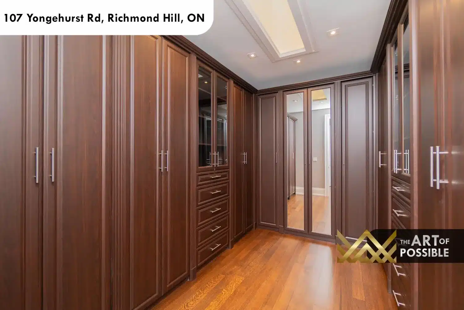 Primary walk-in closet with floor-to-ceiling dark walnut cabinetry, chrome bar pulls and mirrored panels