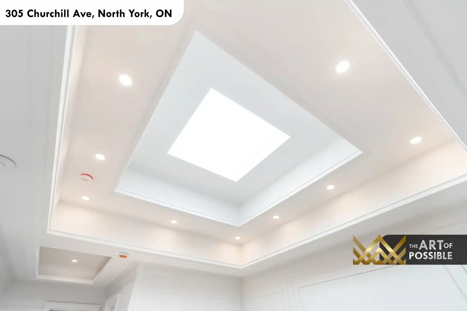 Stepped tray ceiling with large central skylight and ring of recessed pot lights in the primary ensuite