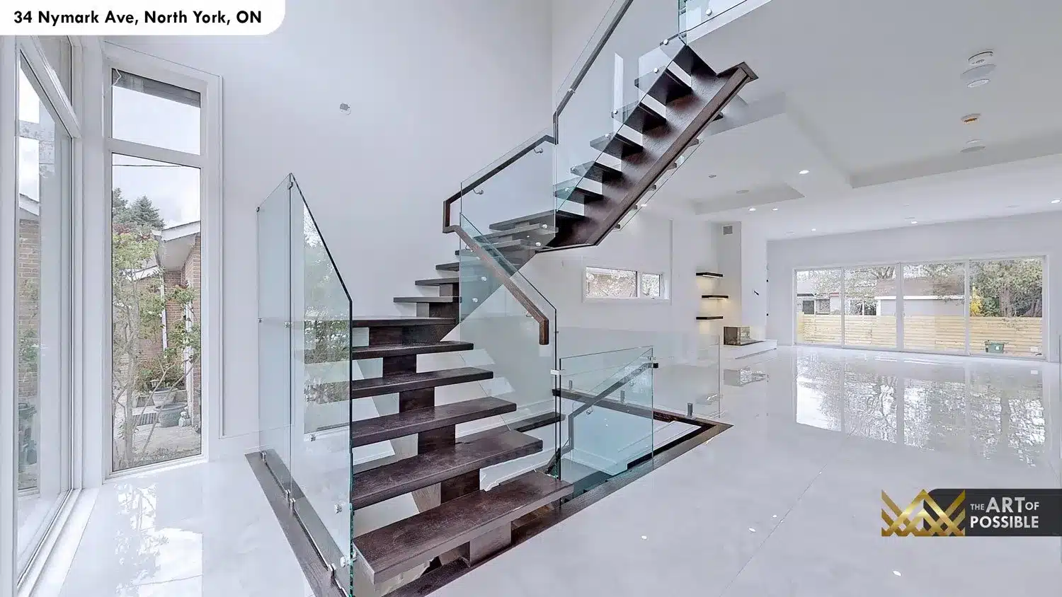 View from main floor through the floating glass staircase toward the open plan living area