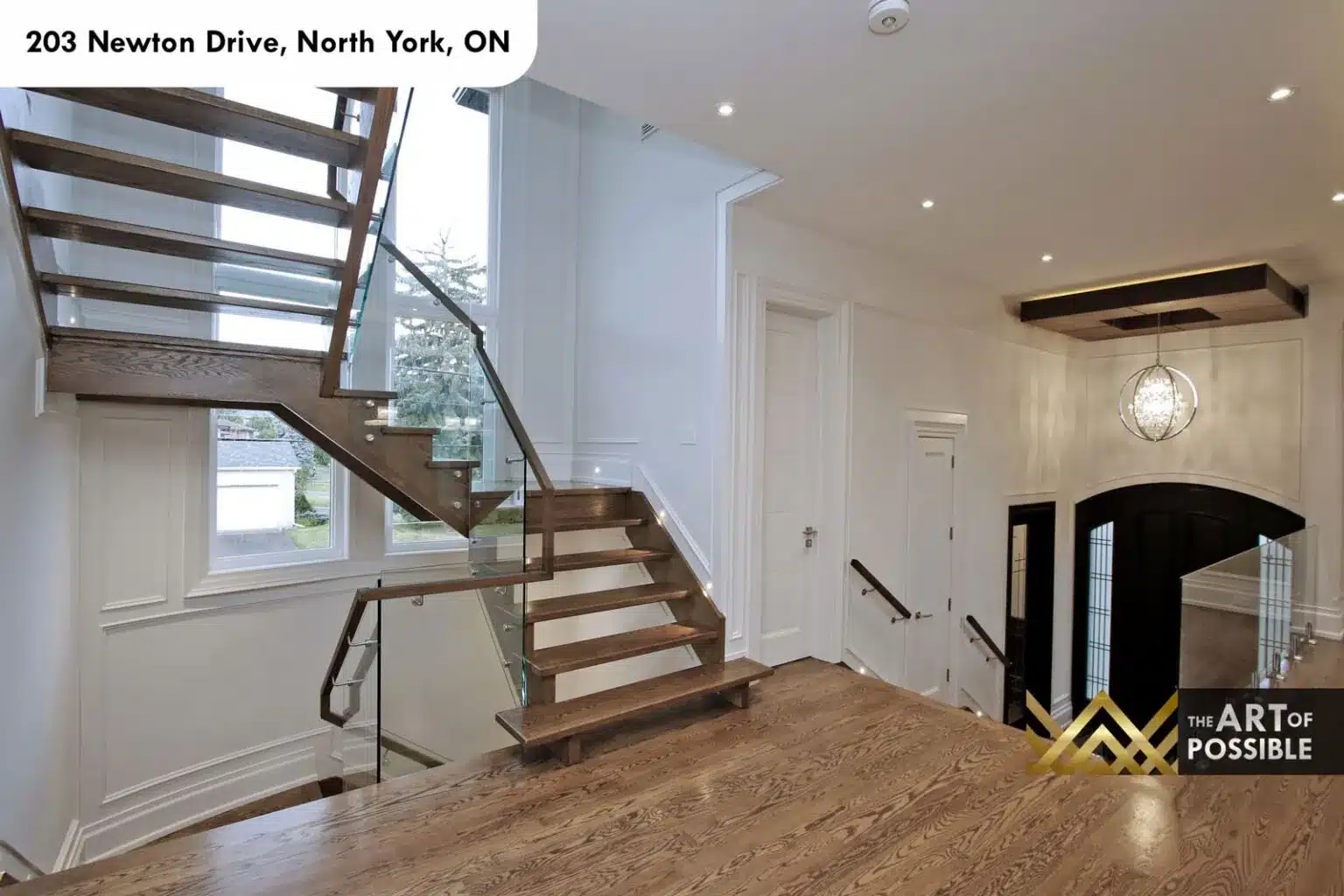 Grand foyer with arched black front door, orb chandelier and marble fireplace beyond