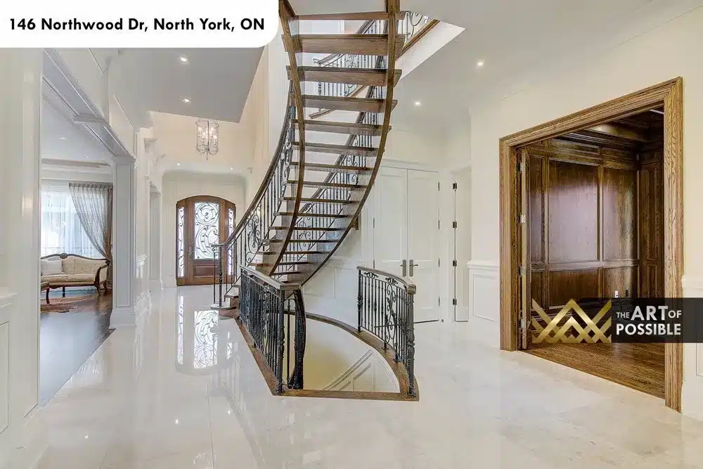 Curved open-tread oak staircase with iron scroll railing in the foyer of 146 Northwood Dr