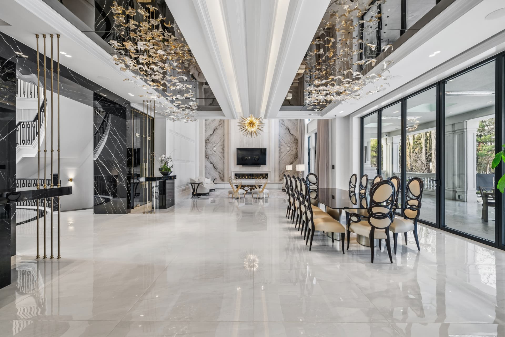 Double-height great room with a long dining table and a lounge with a wall-mounted television in the distance