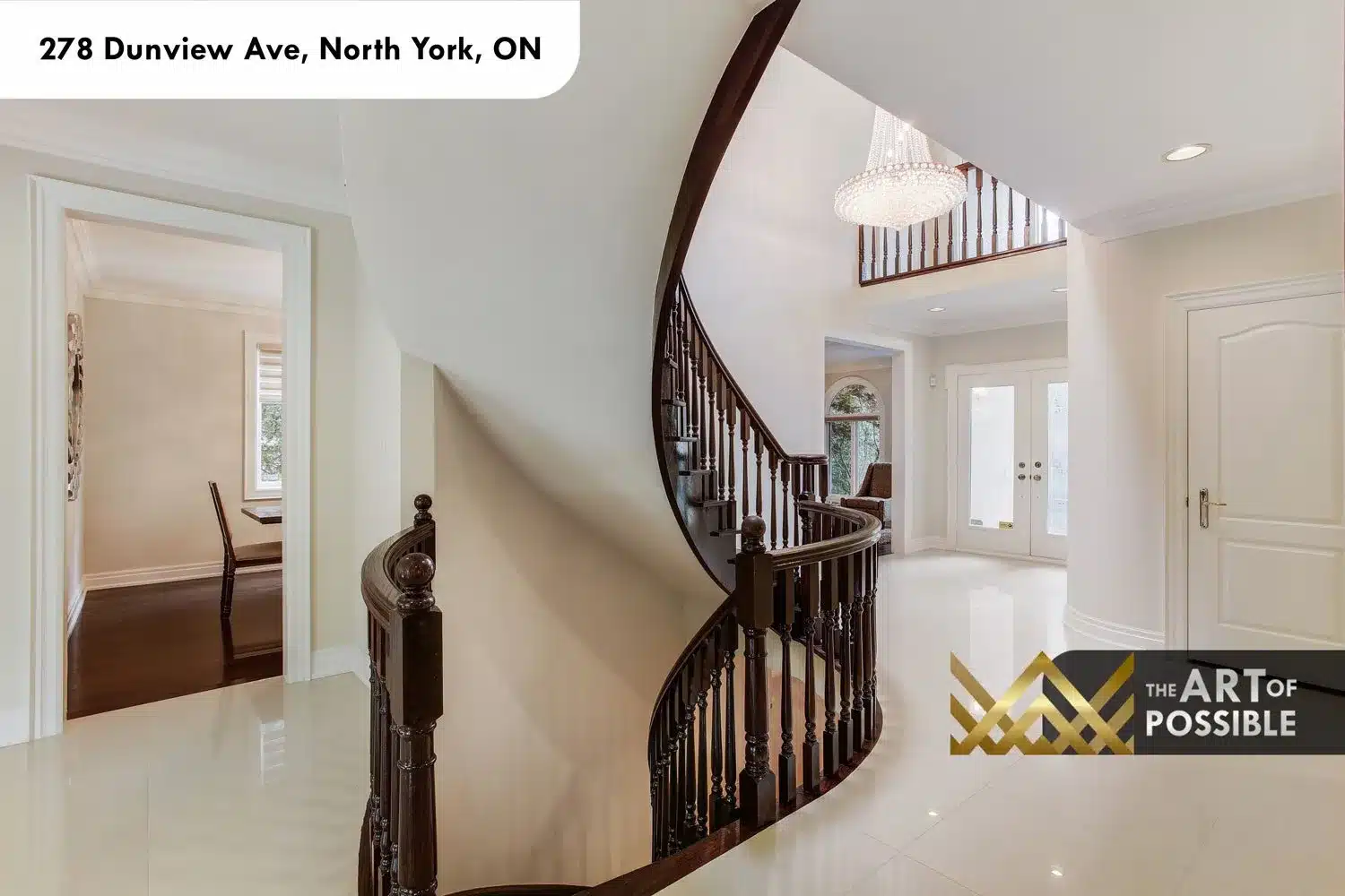 Grand foyer view showing the full arc of the curved staircase and crystal chandelier above