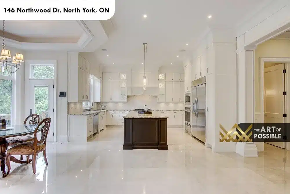 White kitchen cabinetry with dark island, double wall ovens and stainless refrigerator