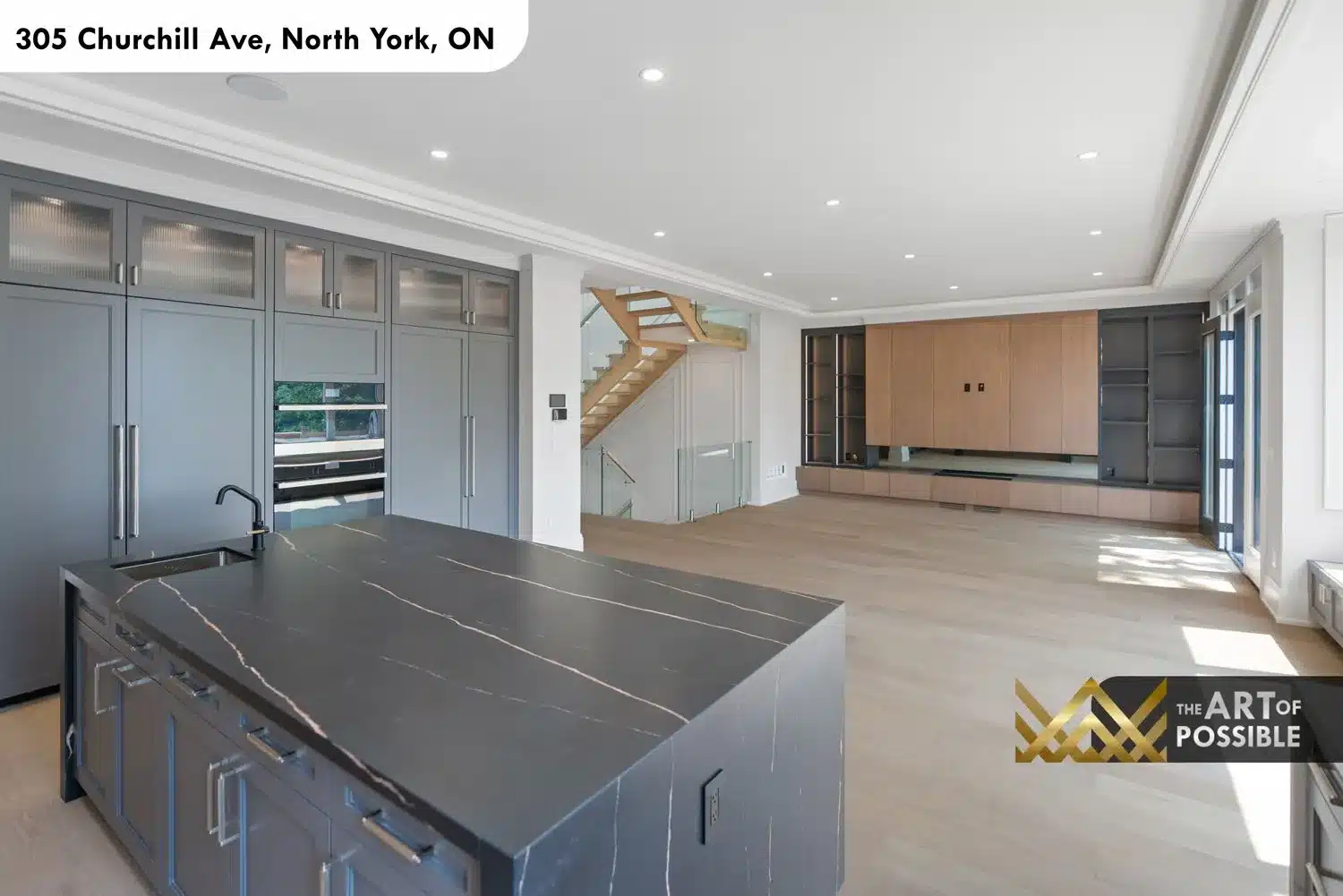 Open plan view from kitchen island showing family room entertainment wall and staircase beyond