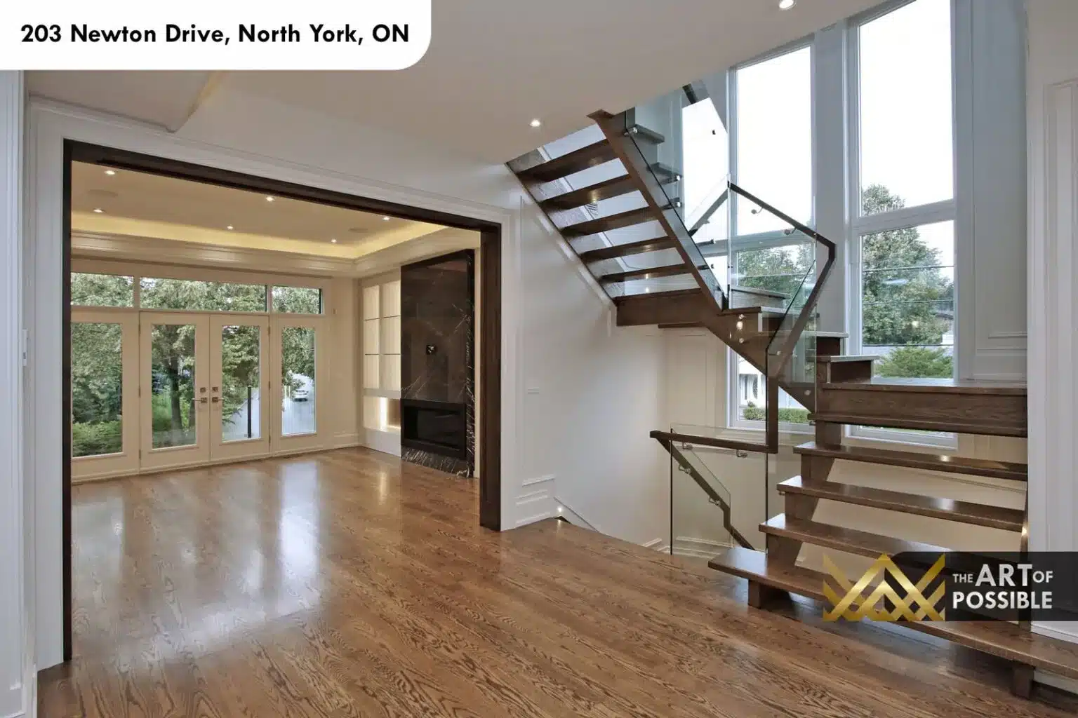 Open-tread oak staircase with glass railings beside floor-to-ceiling windows