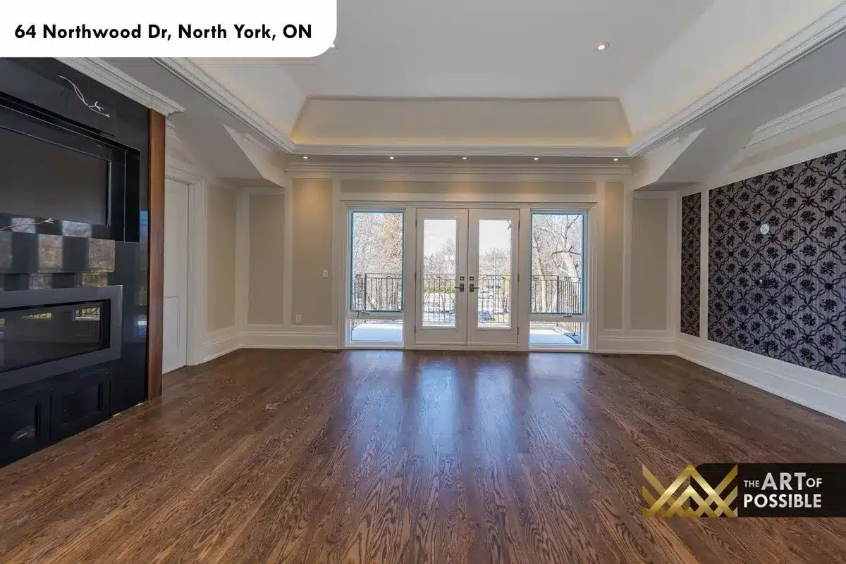 Primary suite with tray ceiling, black fireplace wall and balcony doors
