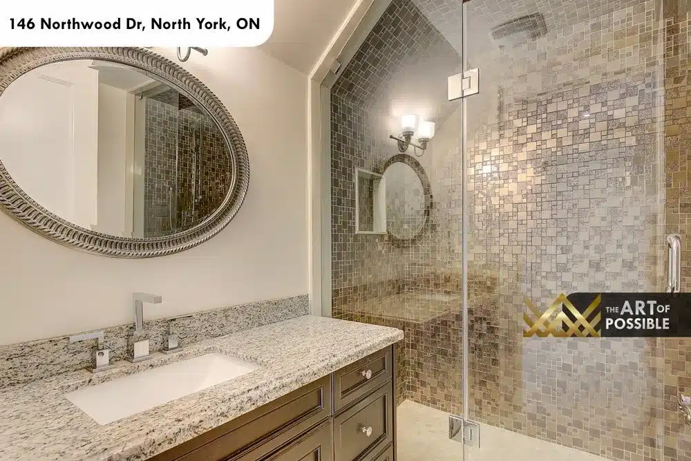 Secondary bathroom with round mirror, espresso vanity and mosaic-tiled glass shower