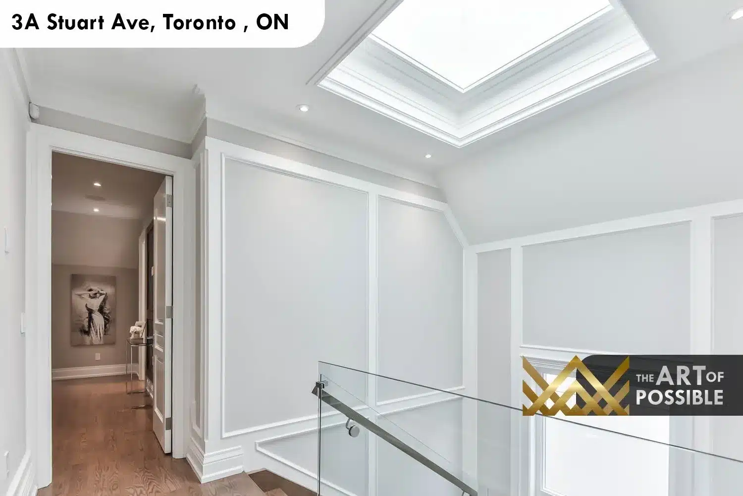 Skylit upper landing with wainscoting panel moulding and glass railing at 3A Stuart Ave