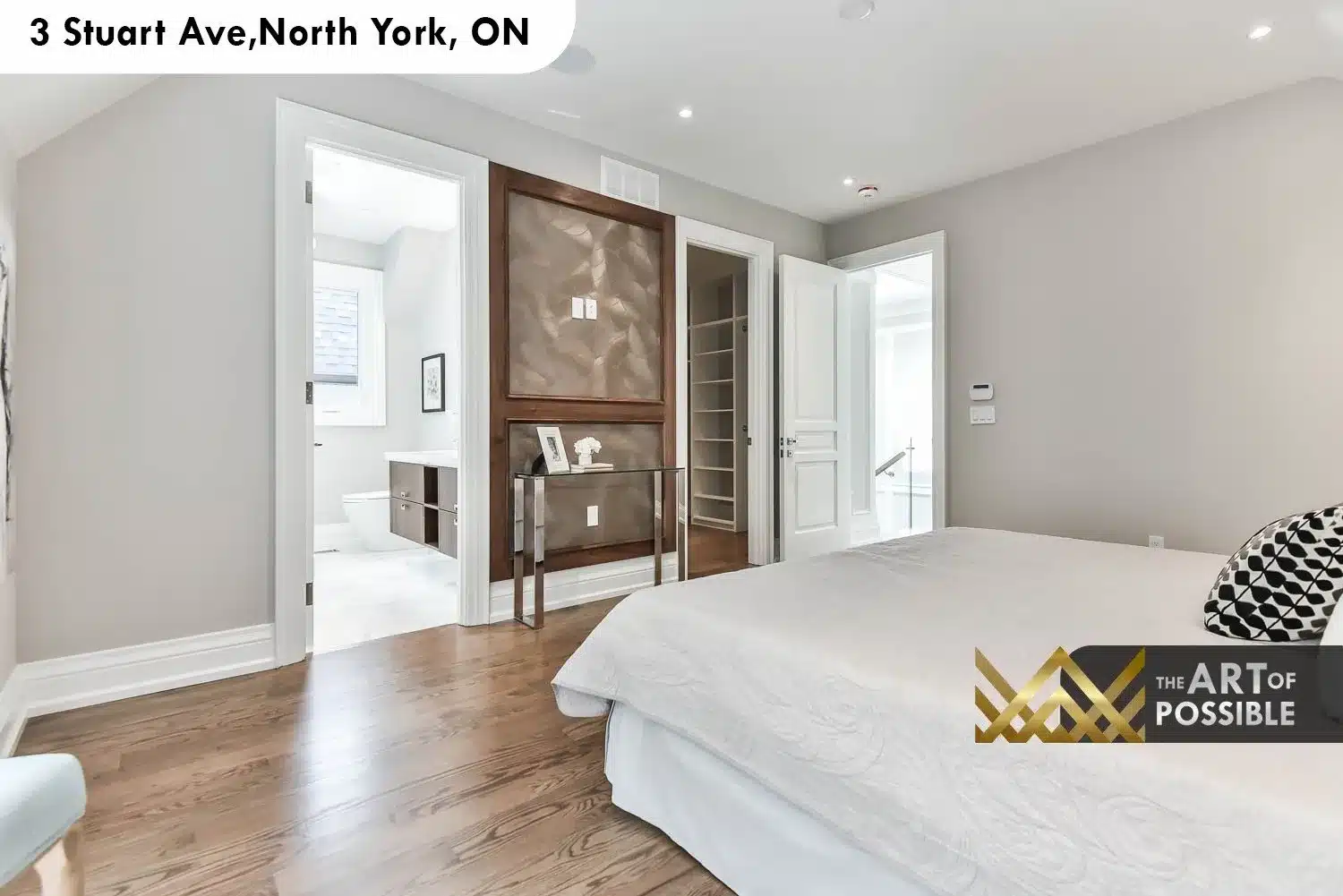 Primary suite showing doors to walk-in closet with white lacquer built-ins and ensuite beyond