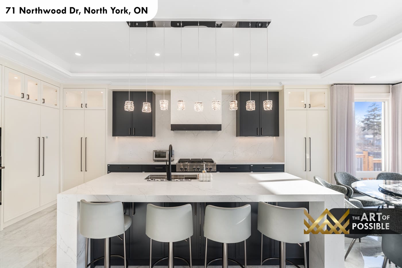 Kitchen with white upper cabinets, dark navy lower cabinets, Calacatta marble backsplash and crystal cube pendants