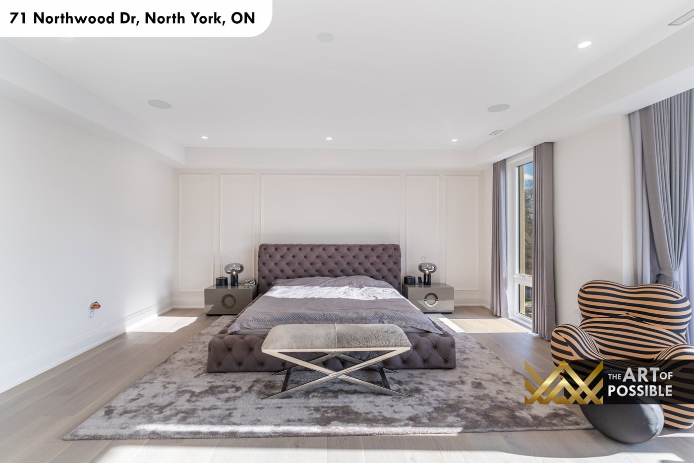 Primary bedroom bed wall with white panel moulding, tufted grey upholstered bed and metallic nightstands