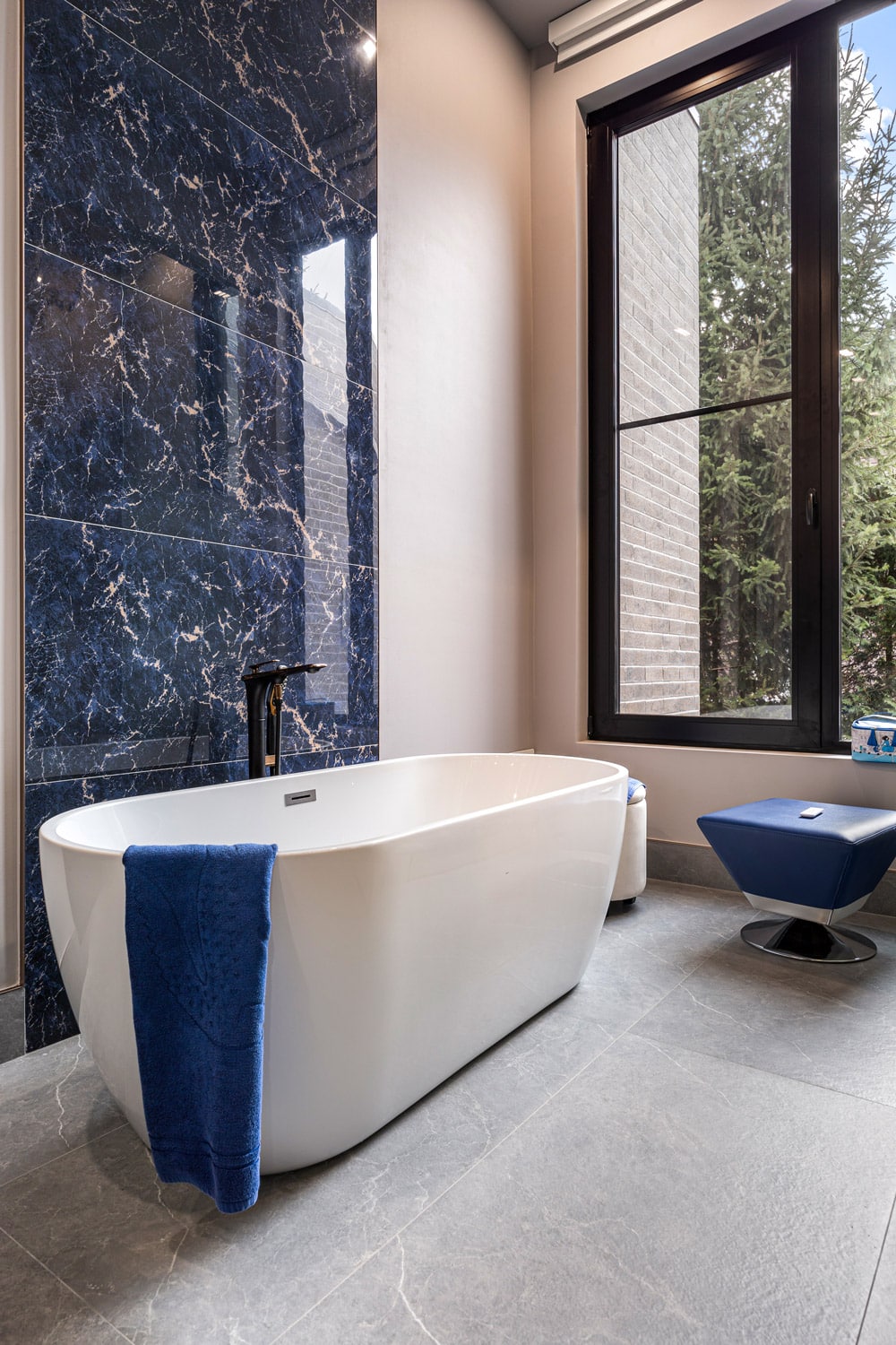 Secondary bathroom at 27 Farr Ave with deep navy blue marble feature wall, freestanding soaker tub and black floor-mounted faucet