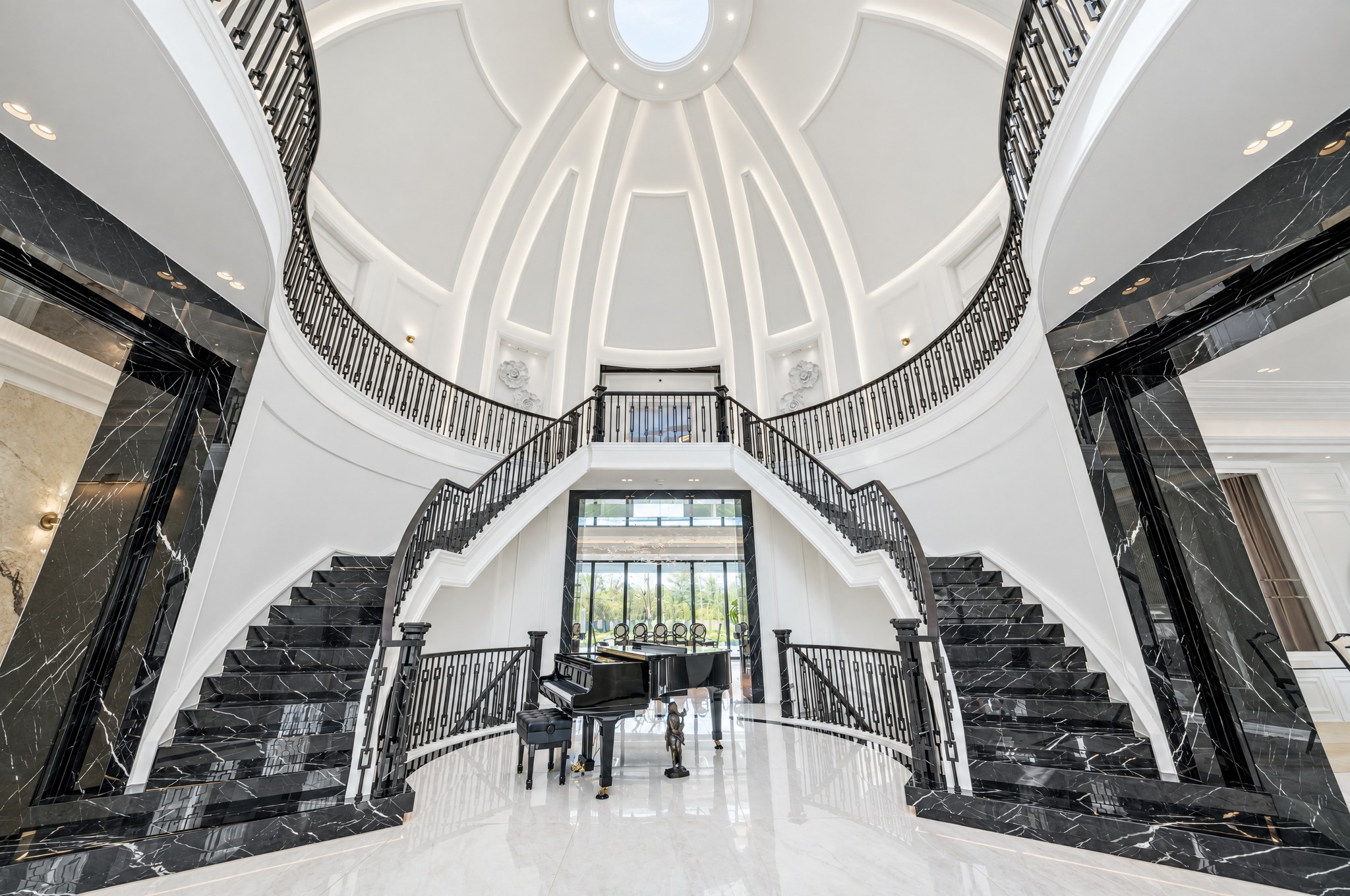 Black marble staircase treads rising to a ribbed plaster dome with oculus skylight