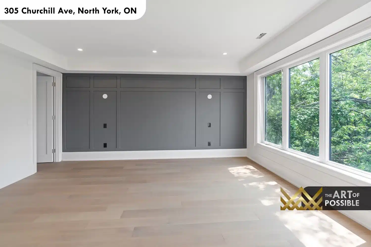 Primary bedroom showing full width charcoal accent wall with panel moulding grid and rear window wall