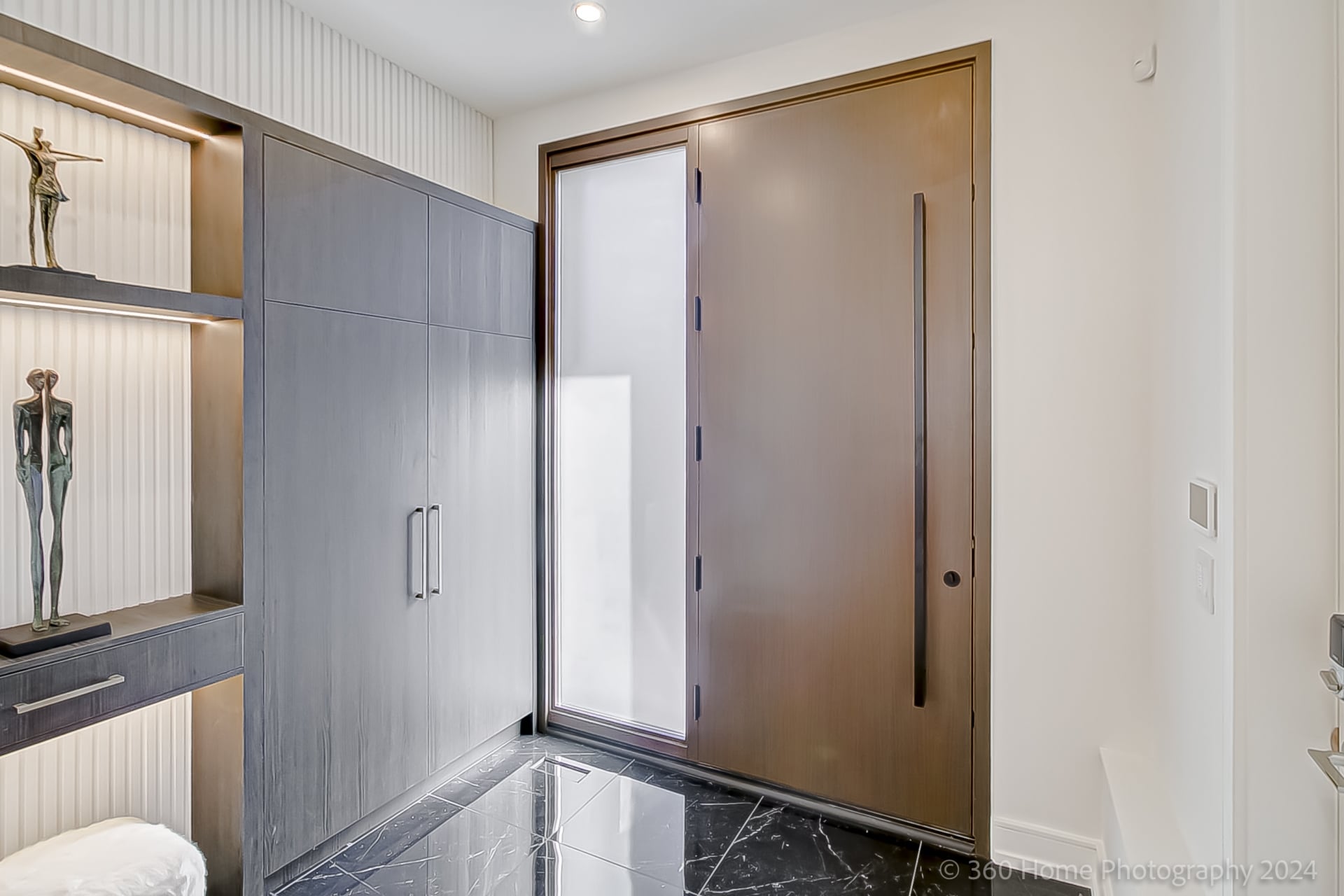 Foyer at 100 Glenvale Blvd with bronze pivot door, dark marble floor tiles and lit built-in shelving