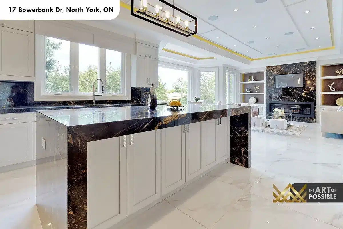 Wide view of kitchen island and family room fireplace wall beyond, showing material continuity