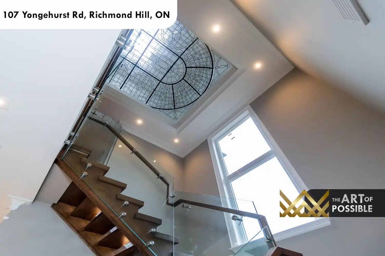 Open-tread oak staircase with glass panel railings and leaded-glass skylight above
