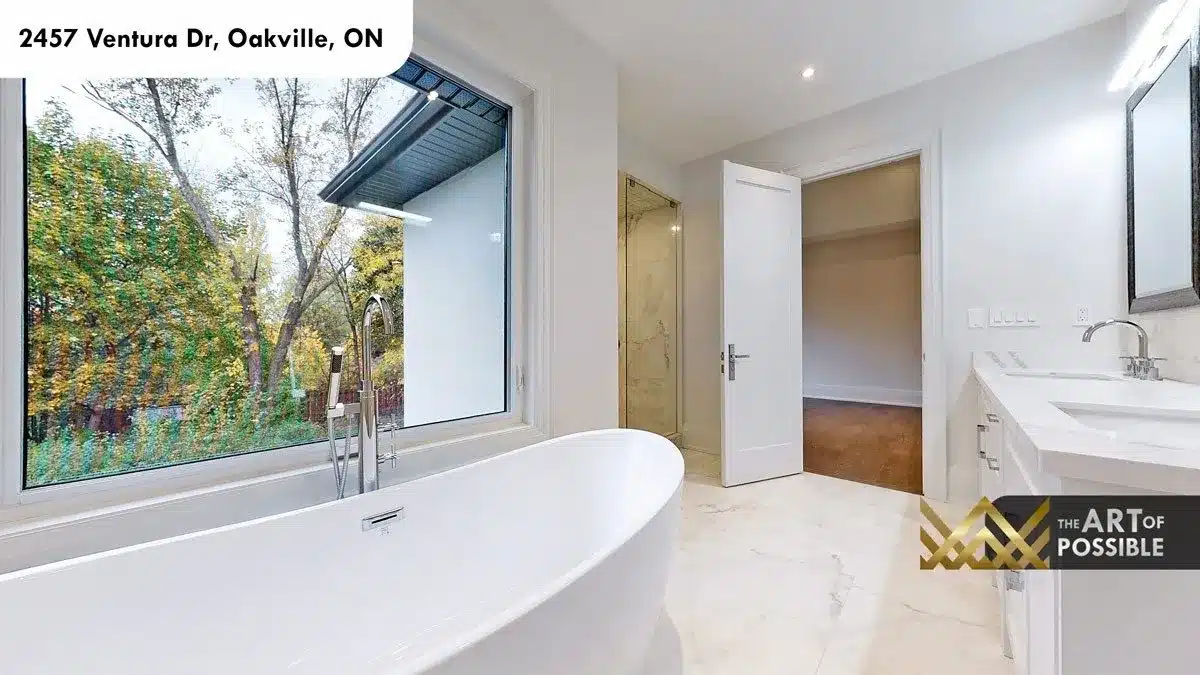 Freestanding oval soaker tub at picture window with garden view in primary ensuite
